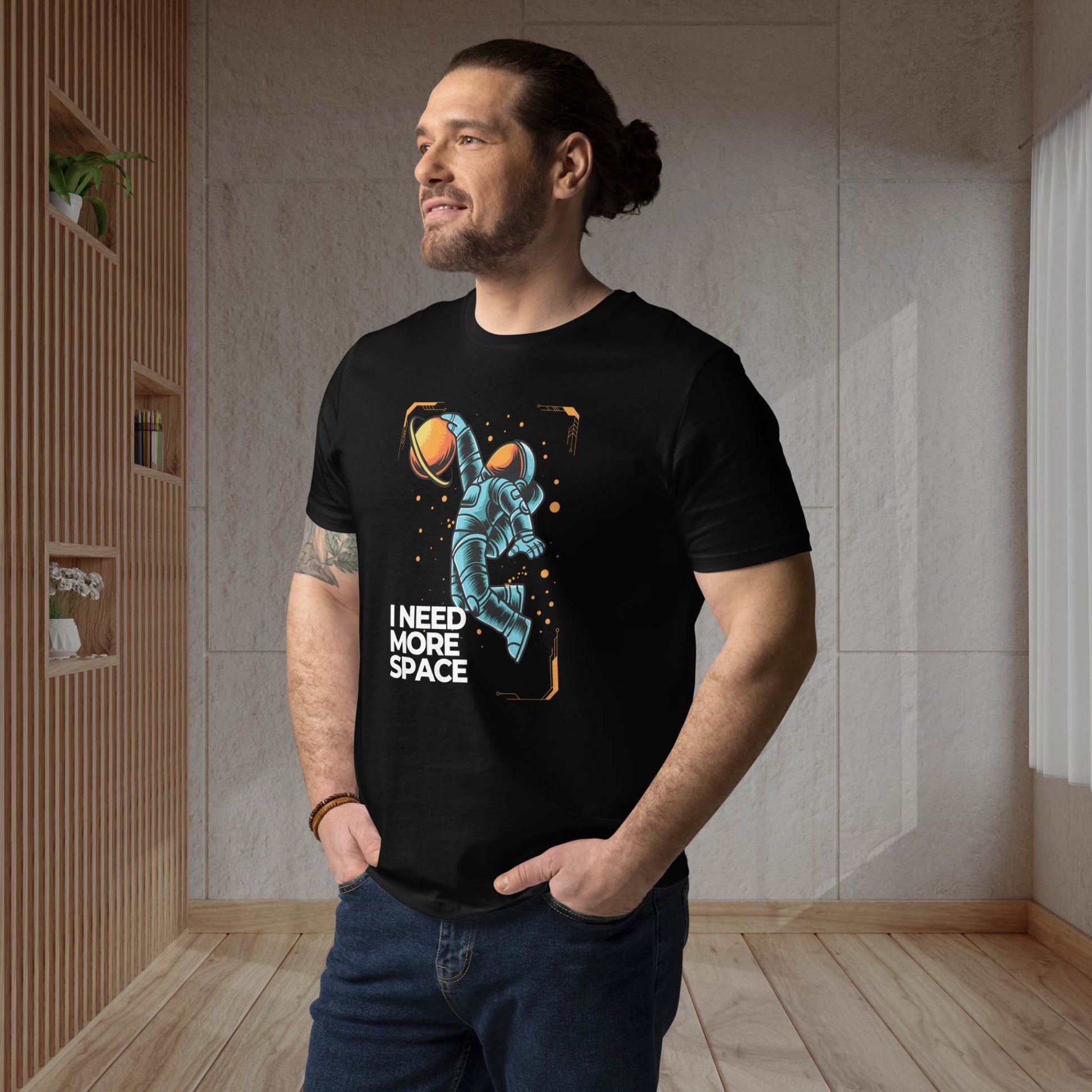 Casually-dressed-40-year-old-male-posing-in-a-living-room-sporting-a-black-tee-with-a-comical-blue-astronaut-illustration