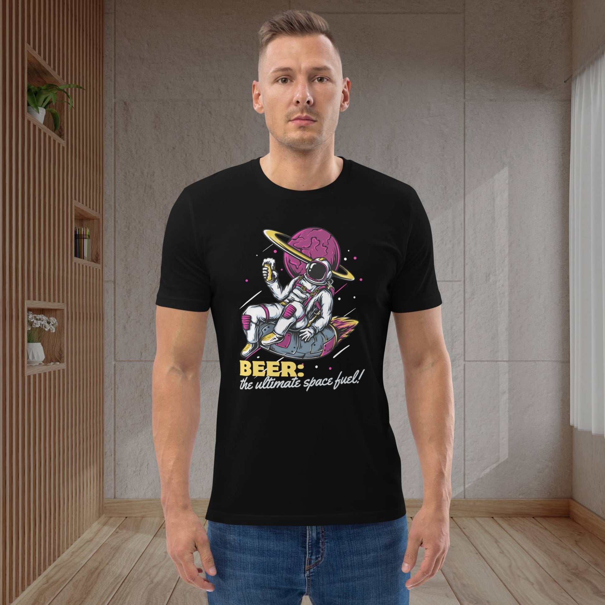 Fashionable-guy-sits-comfortably-in-contemporary-home-wearing-printed-tee-depicting-astronaut-holding-beer-in-outer-space-with-jeans