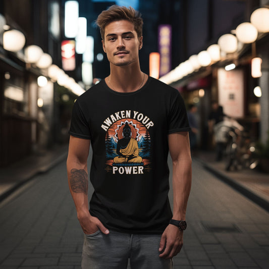 A man in a black "Awaken Your Power" t-shirt with a Buddha graphic stands on a street at night.