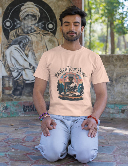 Man meditating in light orange graphic tee with a Buddha design, kneeling on patterned ground with mural behind