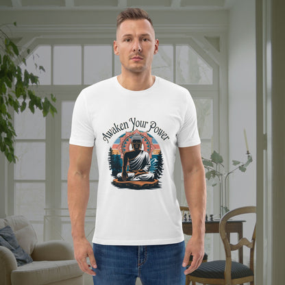 Man in a white graphic shirt with a peaceful, enlightened figure and landscape design, standing indoors