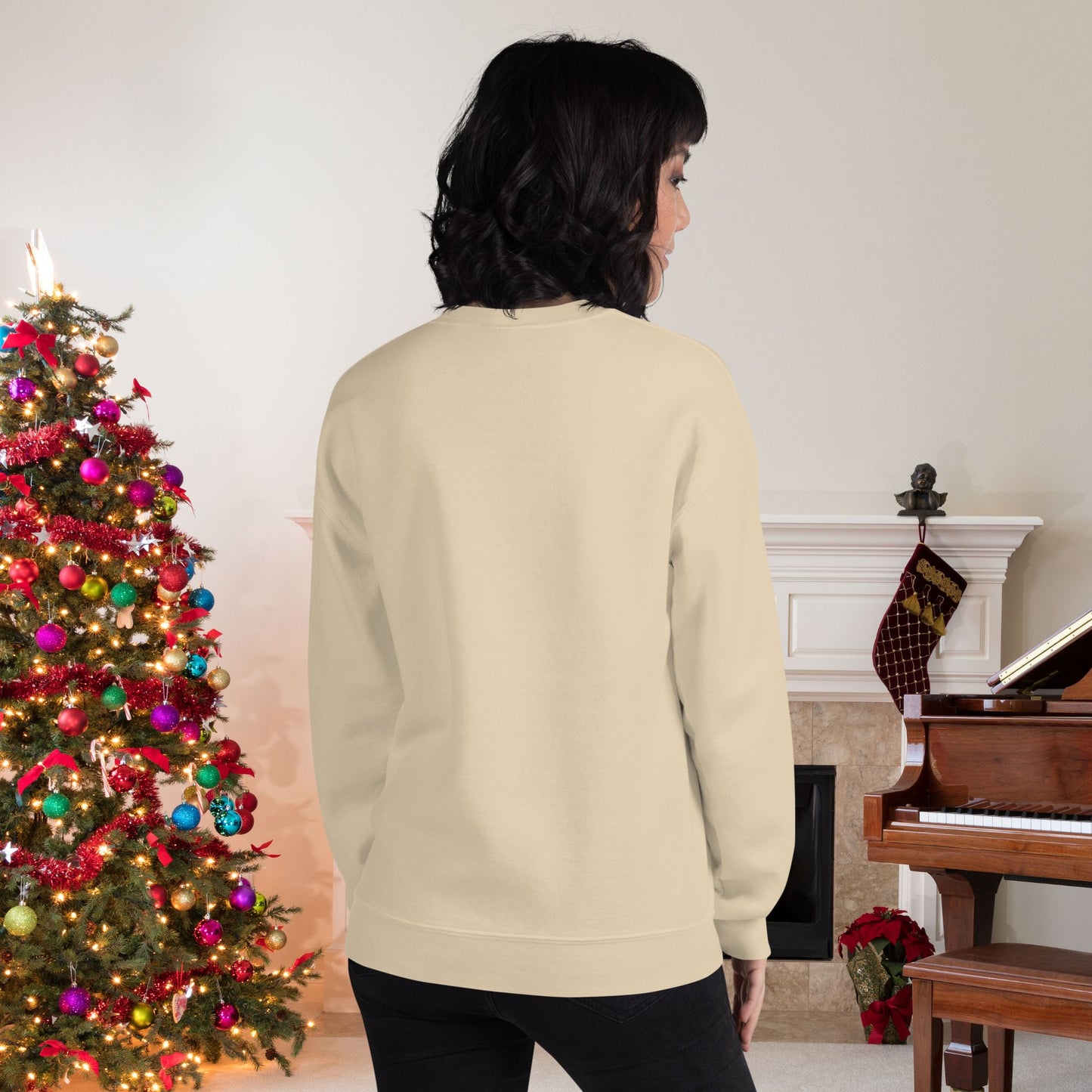 Retro-Christmas-themed-sweatshirt-worn-by-a-young-woman-standing-in-a-cozy-room-decorated-for-the-holidays-with-a-lit-Christmas-tree