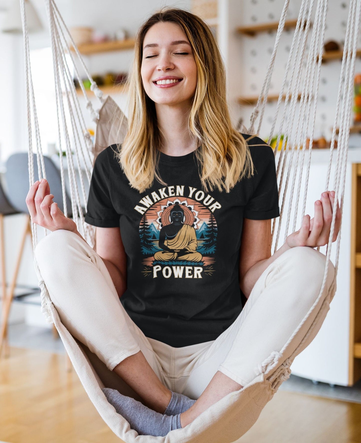 Woman sitting in a hammock wearing a black t-shirt with a Buddha graphic and text.