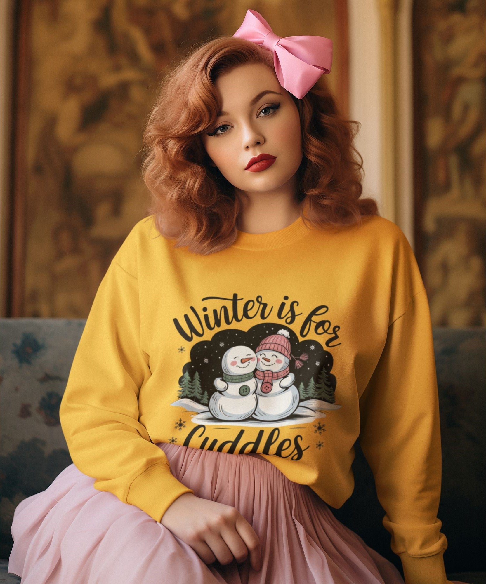 Woman-with-red-curls-wearing-a-gold-sweatshirt-featuring-Winter-is-for-Cuddles-text-styled-with-a-pink-bow-and-pastel-pink-skirt