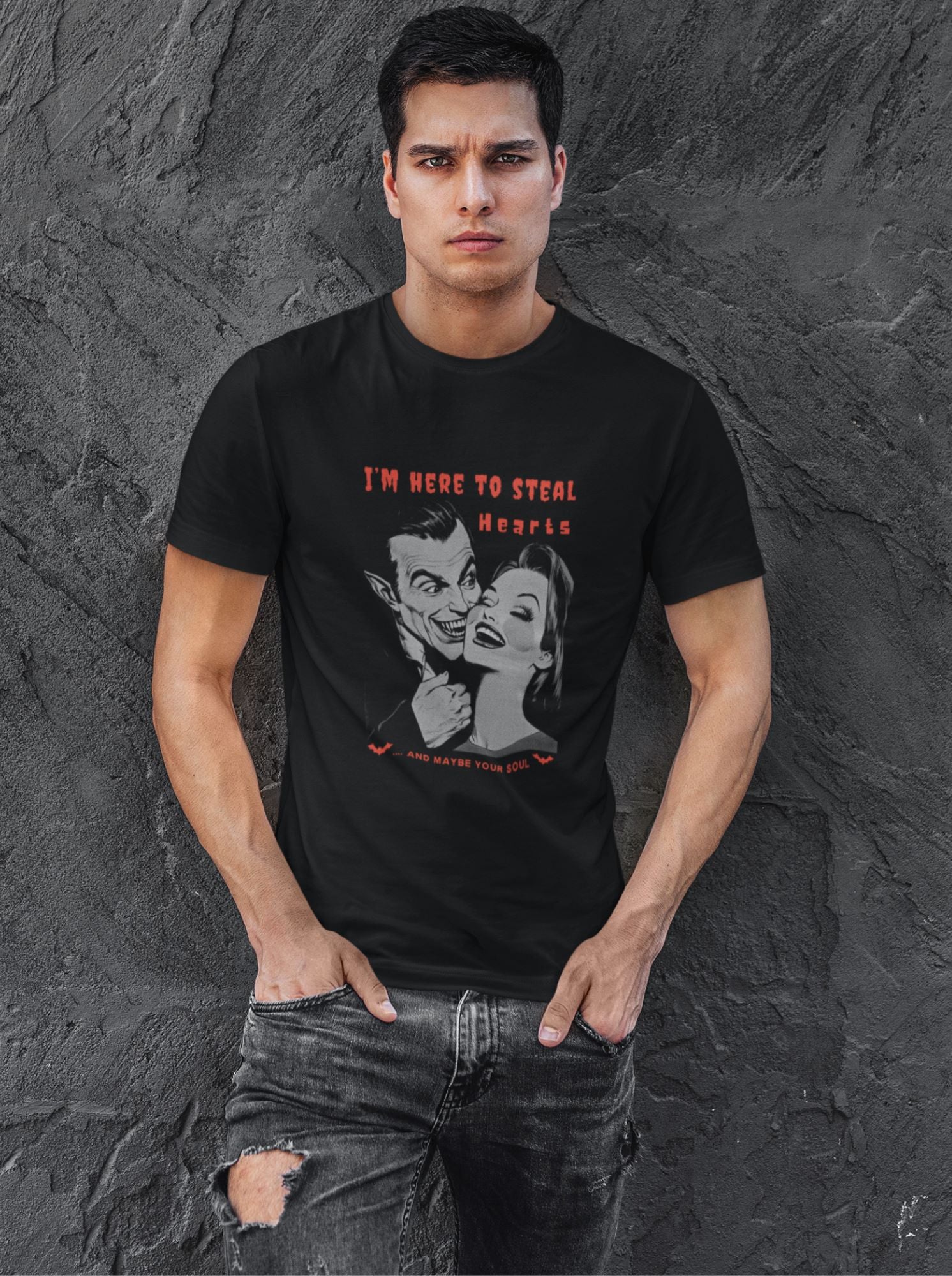 Young-man-against-a-gray-textured-wall-wearing-a-black-t-shirt-with-a-vintage-vampire-print-for-Halloween