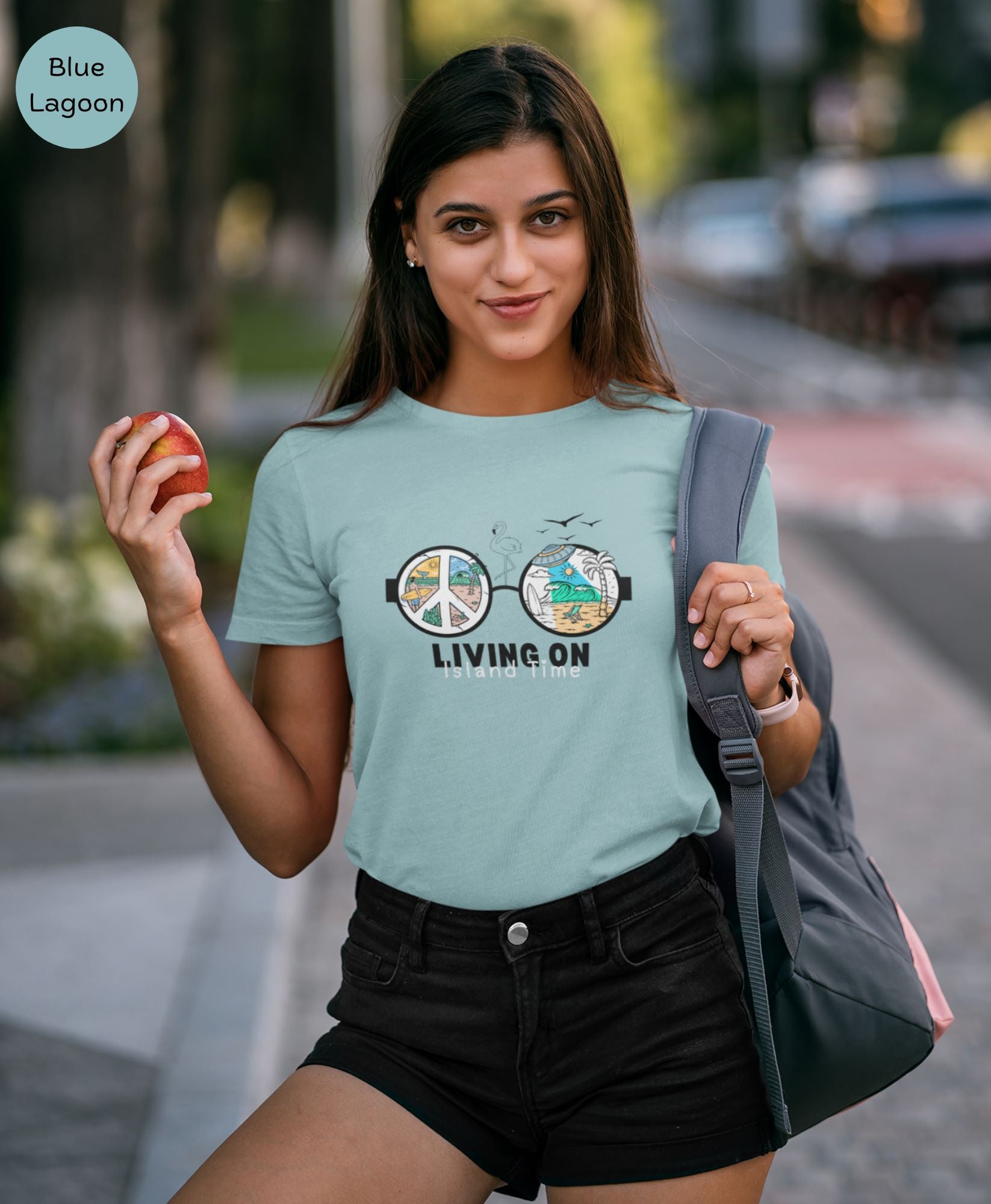 a-young-woman-with-brown-hair-holding-an-apple-posing-for-her-dating-profile-wearing-a-lagoon-blue-t-shirt-and-black-shorts