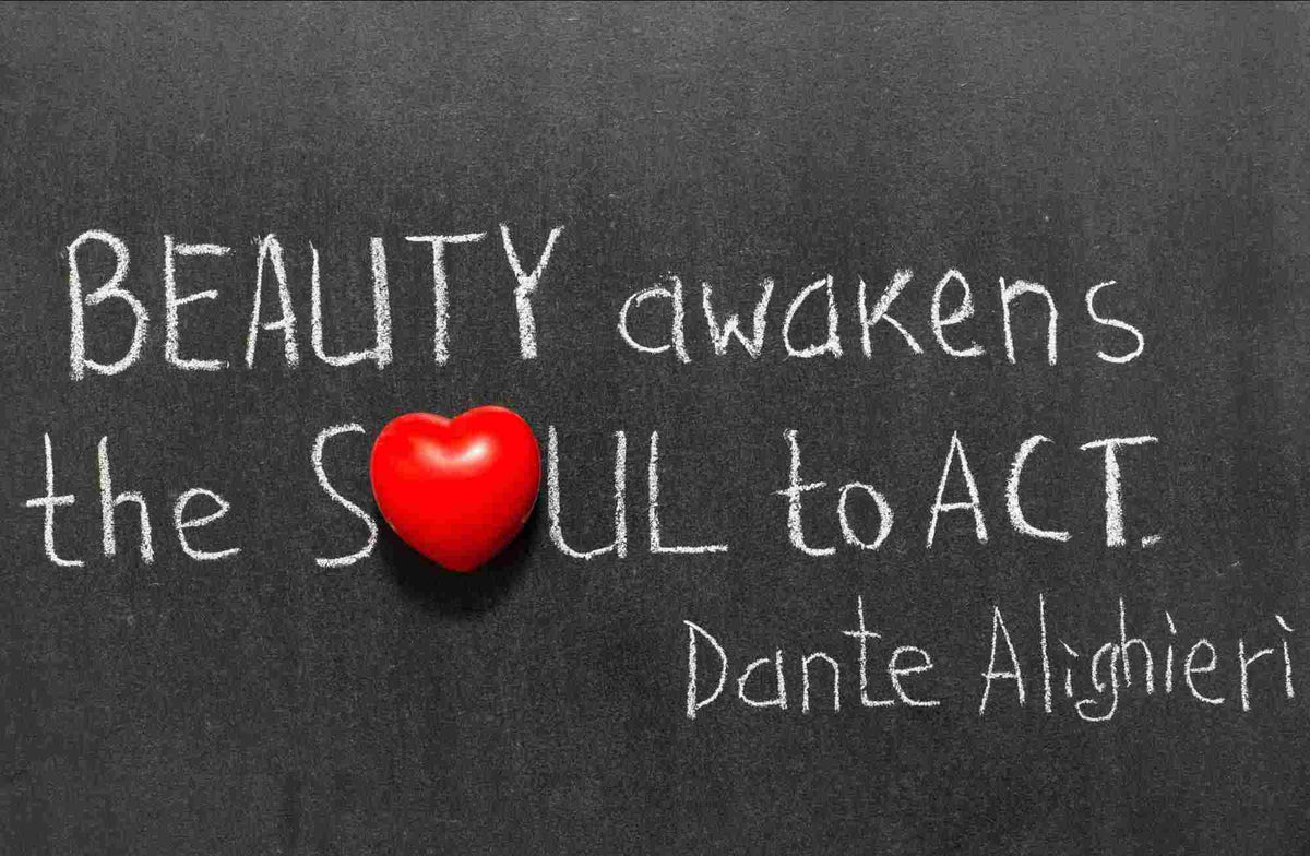 Chalk-style text on a dark chalkboard reading 'BEAUTY awakens the SOUL to ACT.' with a red heart symbol replacing the letter O, and the name Dante Alighieri written below.