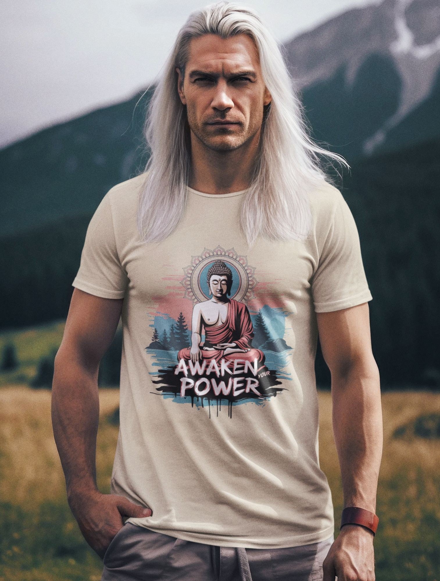A man with long white hair wears a beige t-shirt featuring a Buddha meditation graphic with sacred geometry in the background