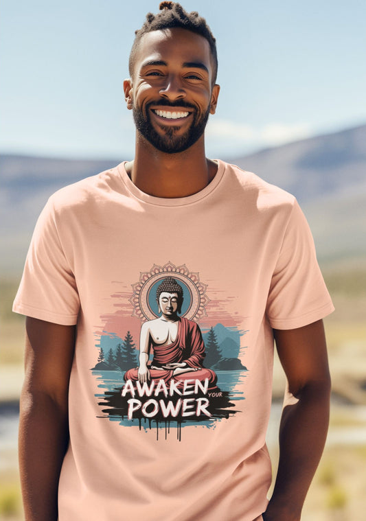 A man smiles, wearing a pink t-shirt with a buddha meditation graphic and the text 
'awaken your power'.