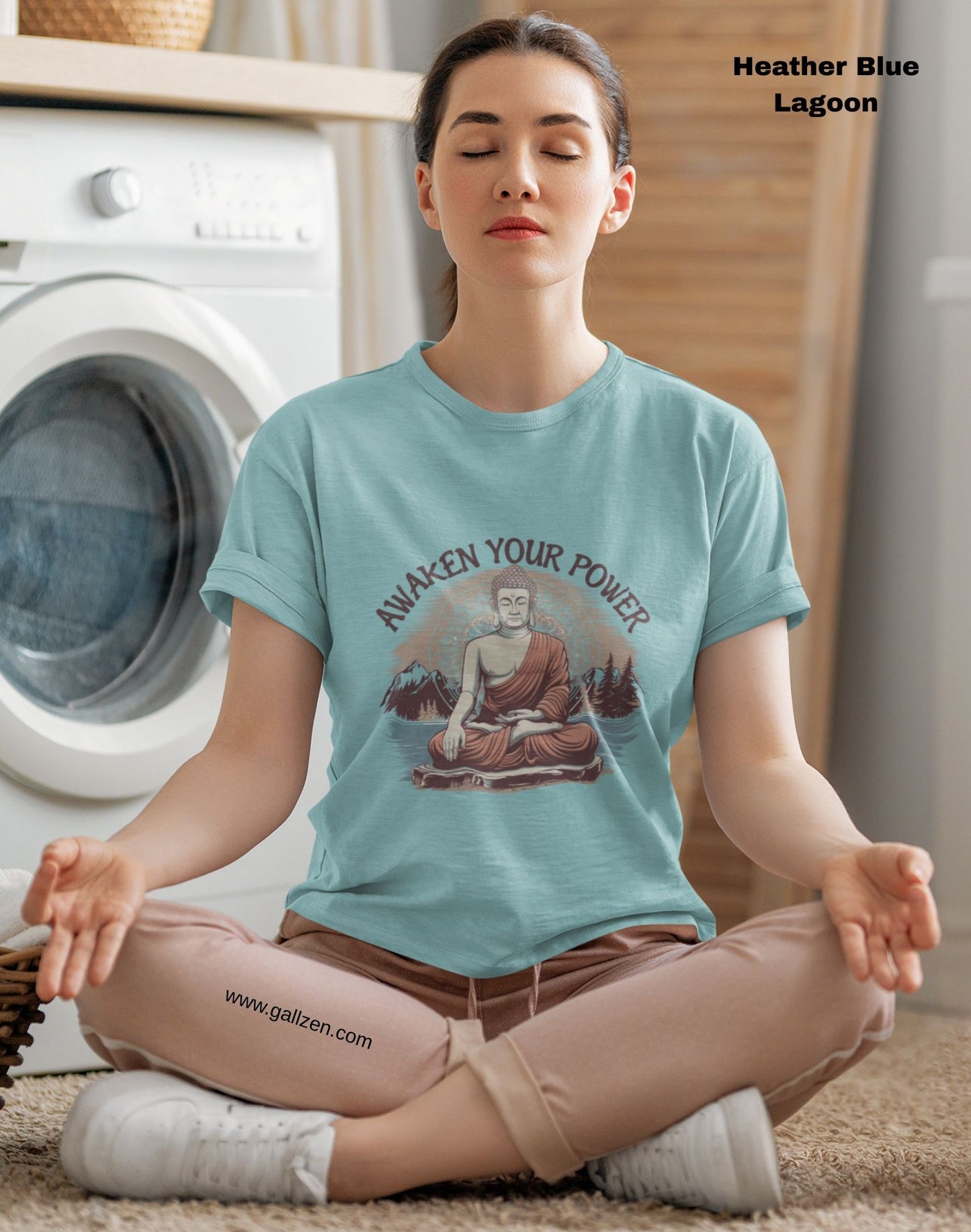 A person meditating while wearing a light blue t-shirt with a Buddha design and the words "Awaken Your Power''.