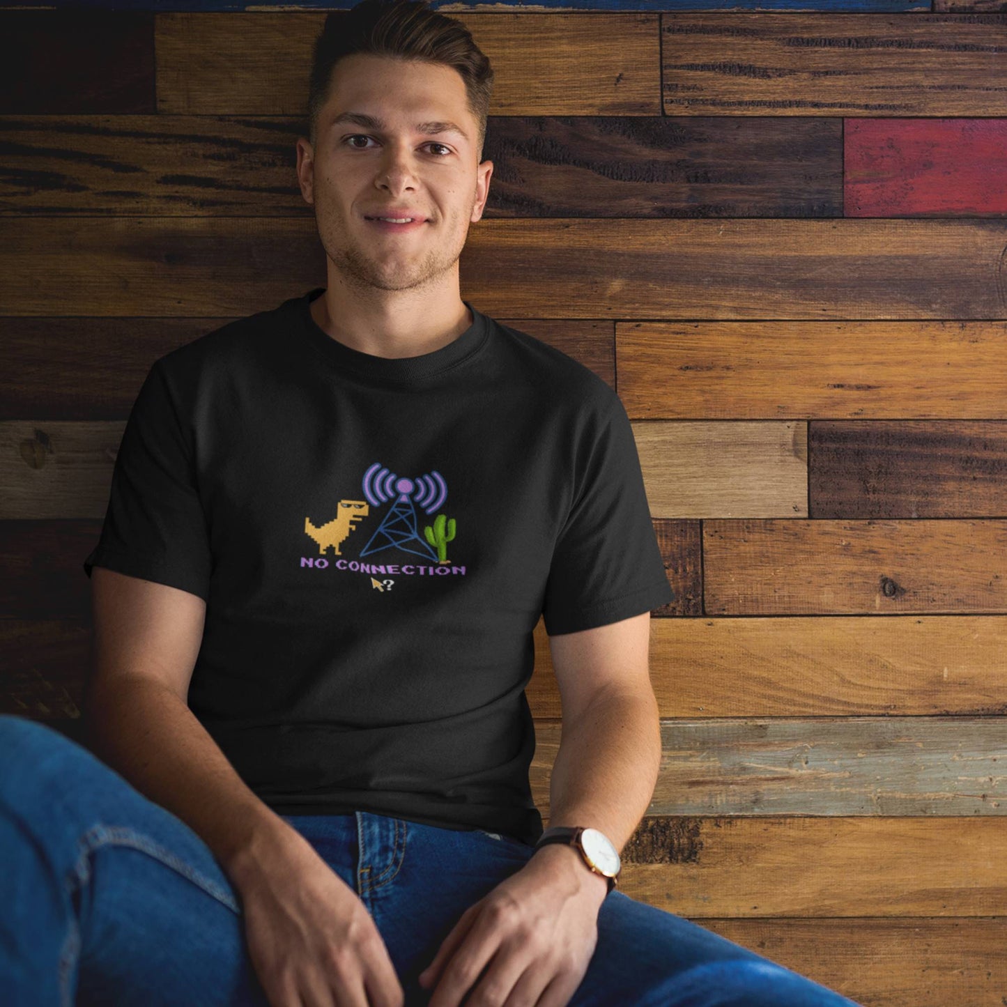 man-wearing-a-funny-black-t-shirt-while-sitting-against-a-wooden-wall-in-a-modern-living-room