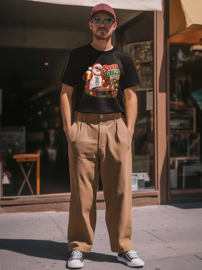 Man wearing a black Santa grilling Christmas shirt tucked into tan wide-leg trousers, with a burgundy cap, sunglasses, and sneakers outside a storefront.