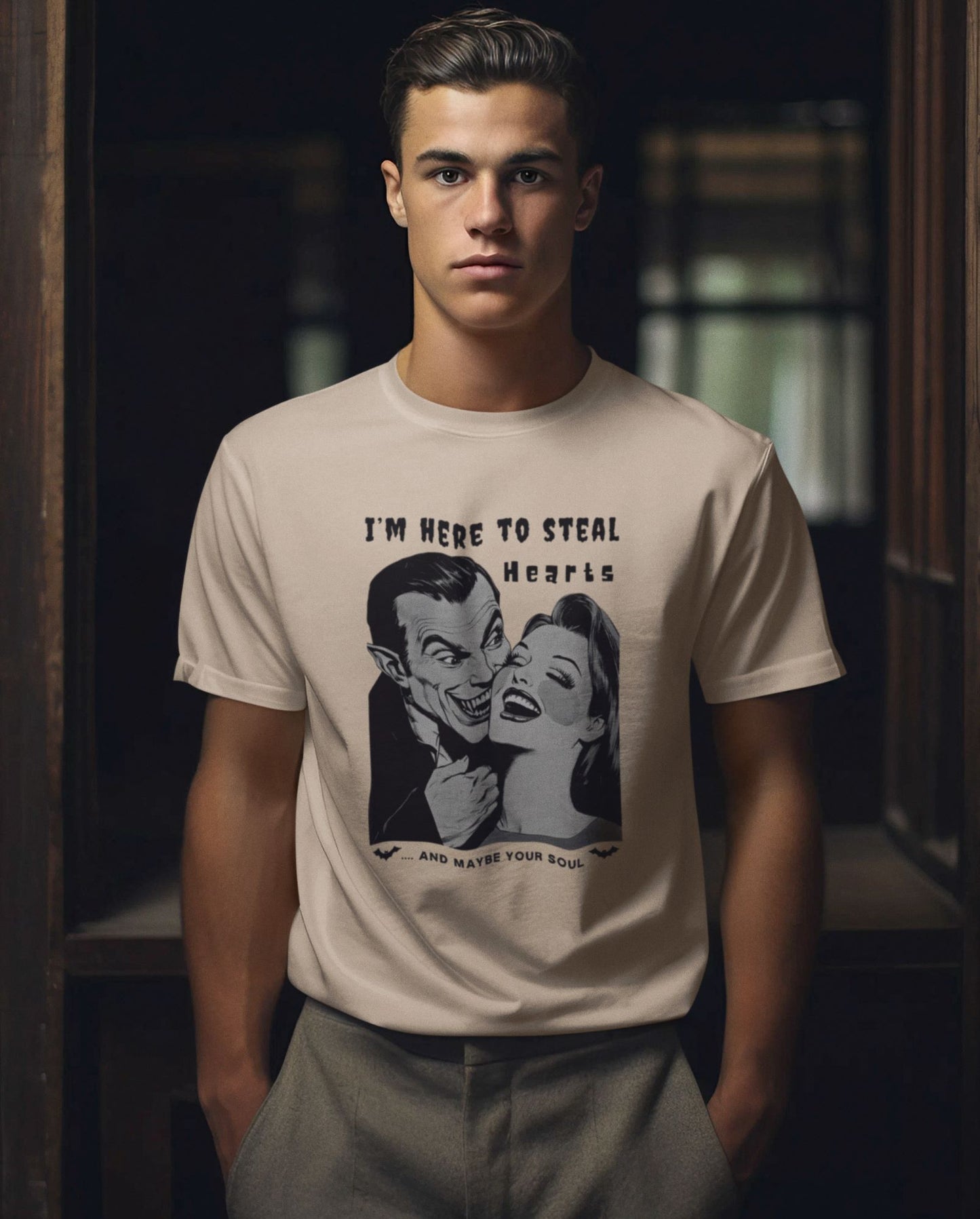 young-man-model-in-a-sand-colored-t-shirt-featuring-a-retro-horror-movie-style-graphic-of-Dracula-and-a-woman-with-playful-text