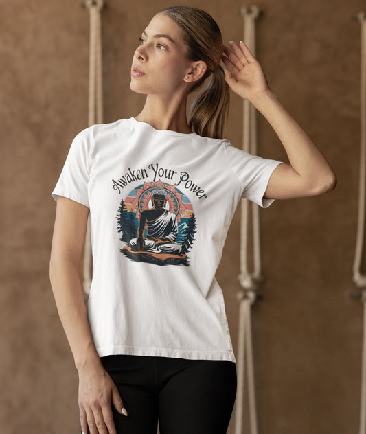 A woman with light brown hair wears a white zen power t-shirt featuring a graphic of Buddha meditating amidst a natural landscape with the text "Awaken Your Power."