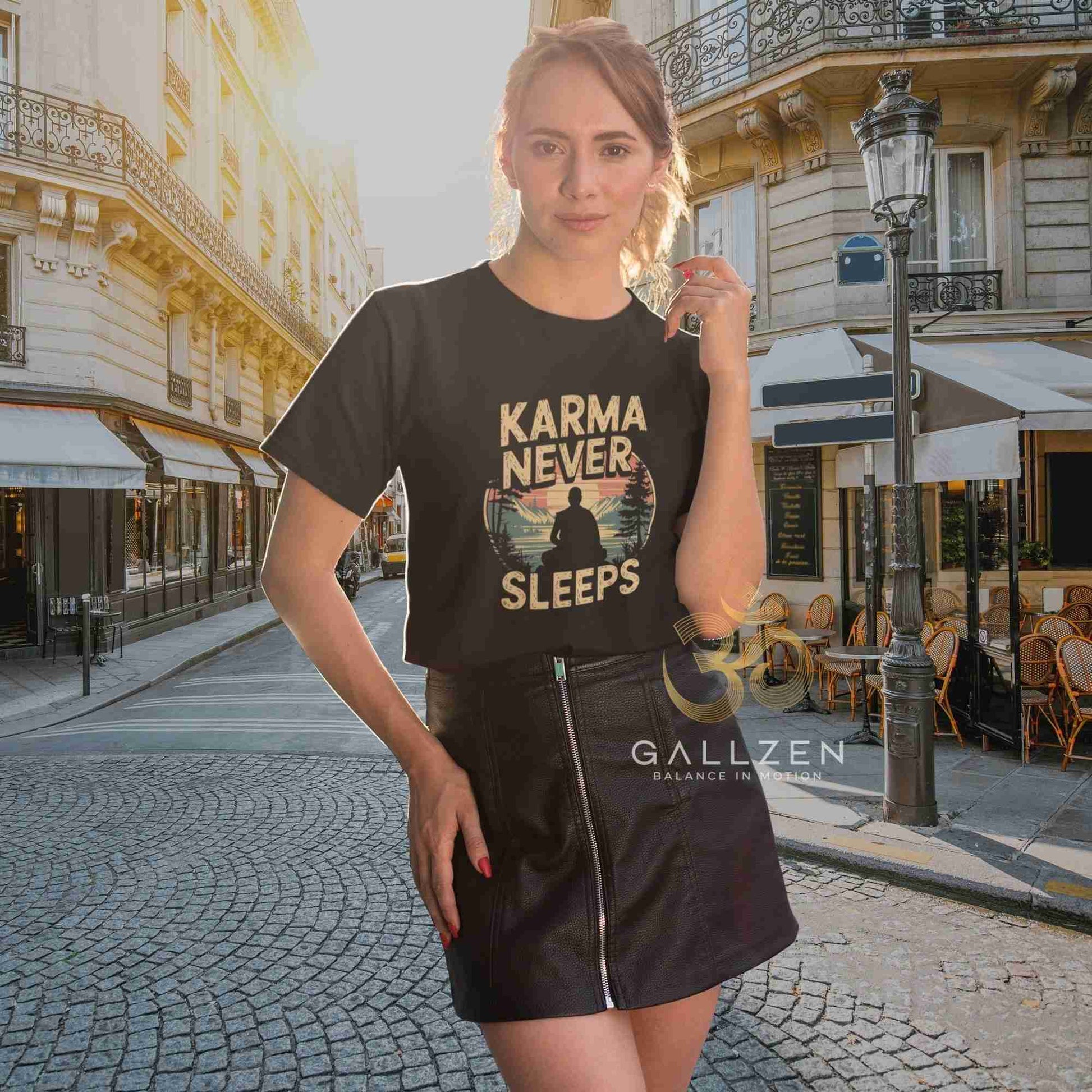 A woman stands on a cobblestone street in front of Parisian-style buildings, wearing a black graphic T-shirt with the words 'KARMA NEVER SLEEPS' and a circular sunset illustration. 
