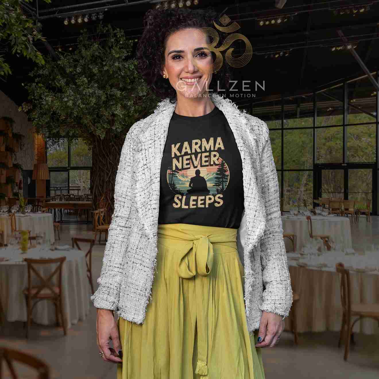 A woman stands in a decorated event venue wearing a black graphic T-shirt with the text 'KARMA NEVER SLEEPS' and a yellow-green tie-waist skirt, styled with a white tweed jacket. 